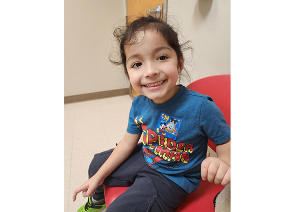 Jonah smiling at the camera sitting in an exam room
