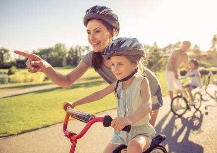 A mother teaches her child how to ride a bicycle