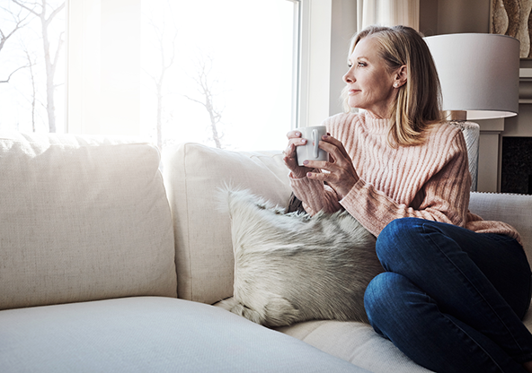 A senior woman drinking coffee and looking out the window